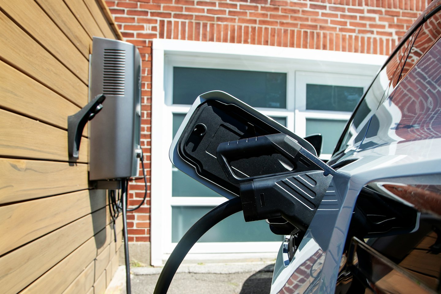 Oplaadkabel voor elektrische auto aangesloten op een grijs voertuig.